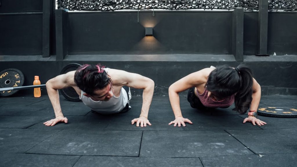 Two adults doing push-ups in an indoor gym setting in Mexico City, promoting a fit and healthy lifestyle.